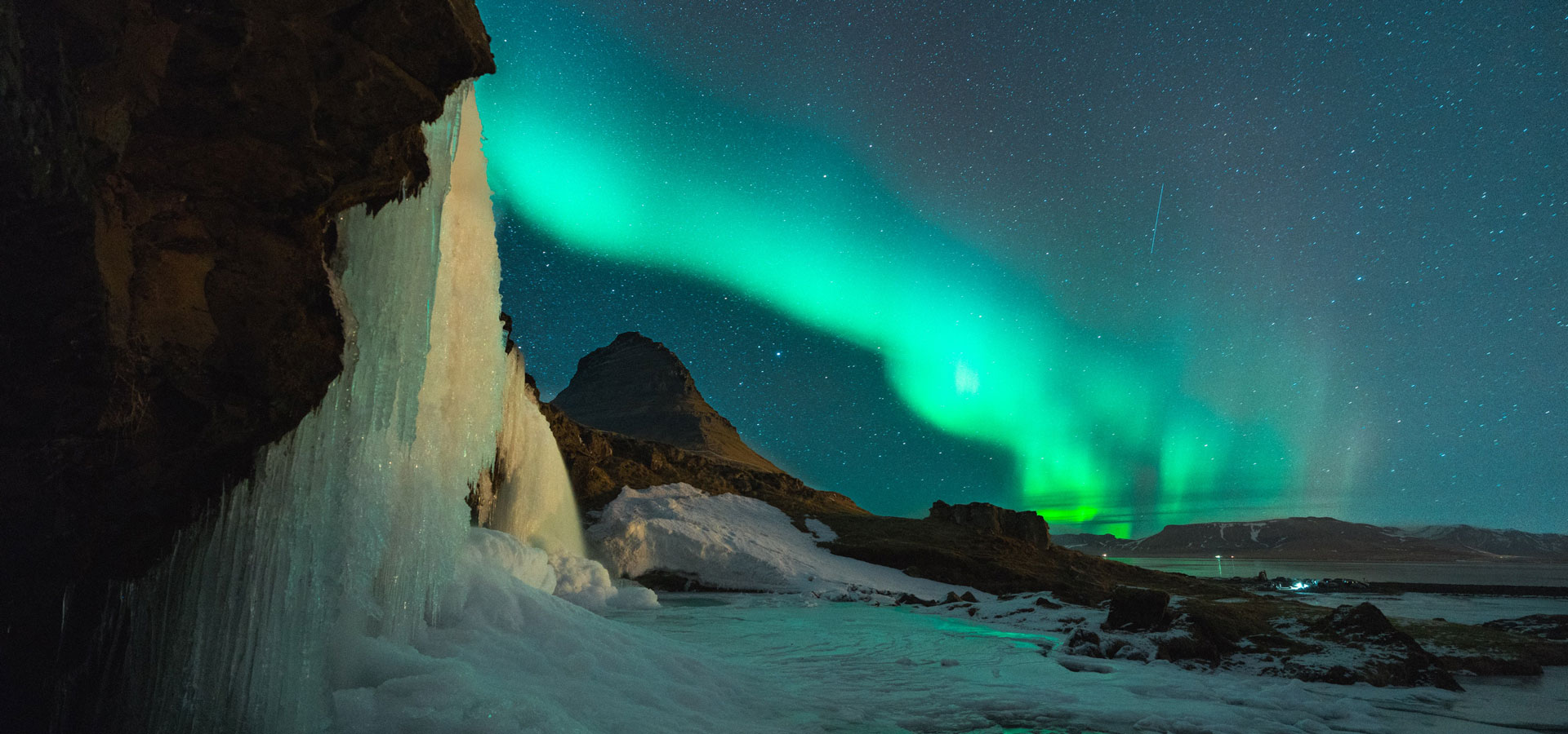 A spectacular display of the Aurora, lighting the night skies in curtains of blues and greens over an ice field.