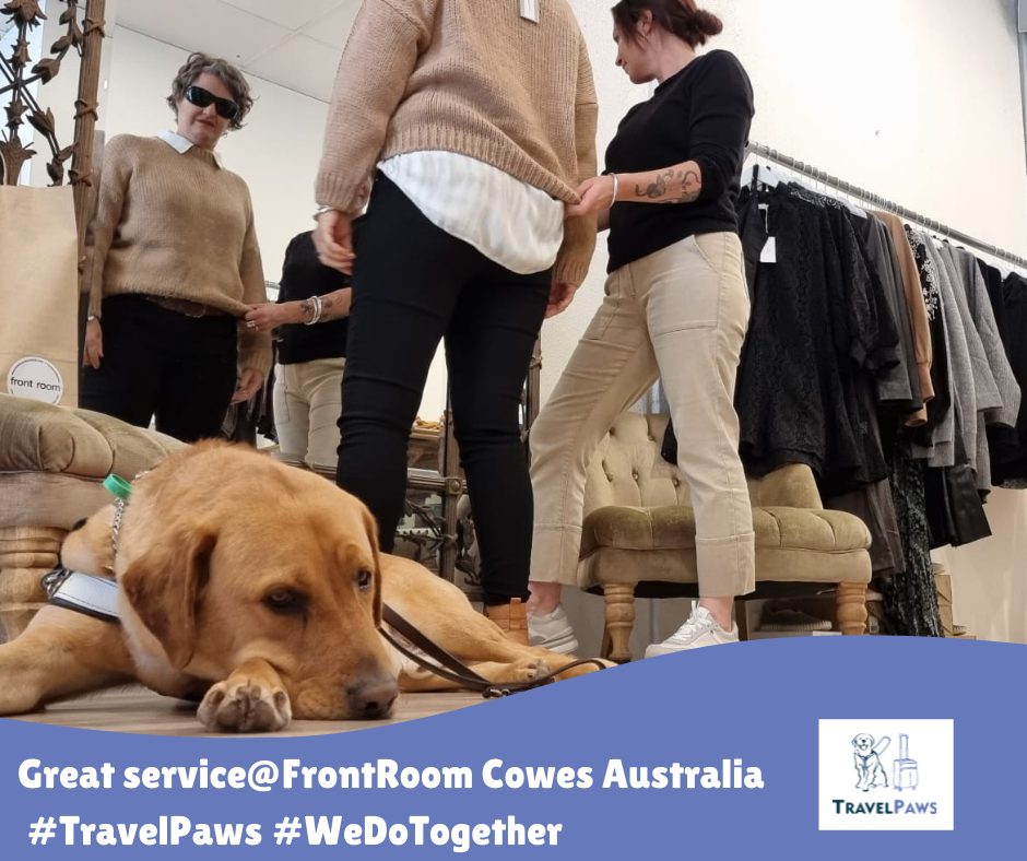 Golden Labrador Assistance Dog Nixon lying down in harness. Behind him Handler Nina is in front of a mirror trying on a beige jumper being helped by the Shop Assistant. Image adorned with TravelPaws logo, Caption reads 'Great service@Front Room, Cowes, Australia'. Hash tags #TravelPaws #WeDoTogether