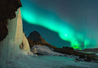 A spectacular display of the Aurora, lighting the night skies in curtains of blues and greens over an ice field.